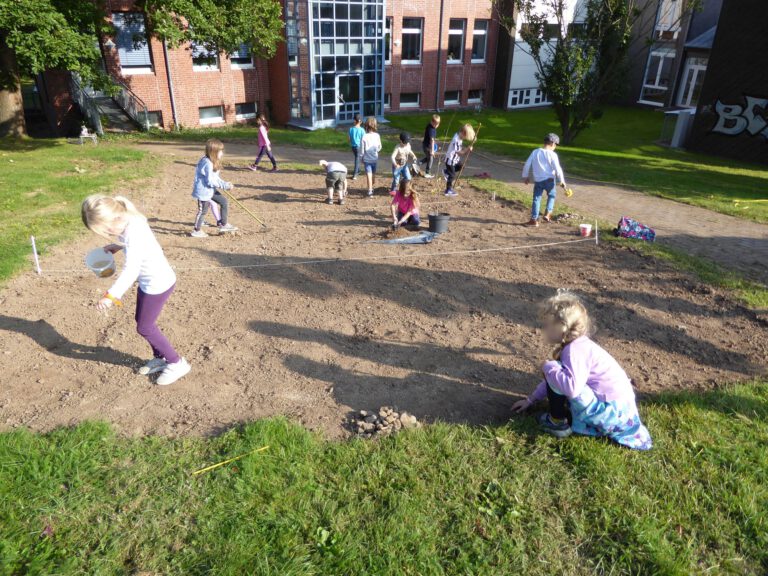 Die Kinder bereiten die Fläche vor und bringen das Saatgut aus.
